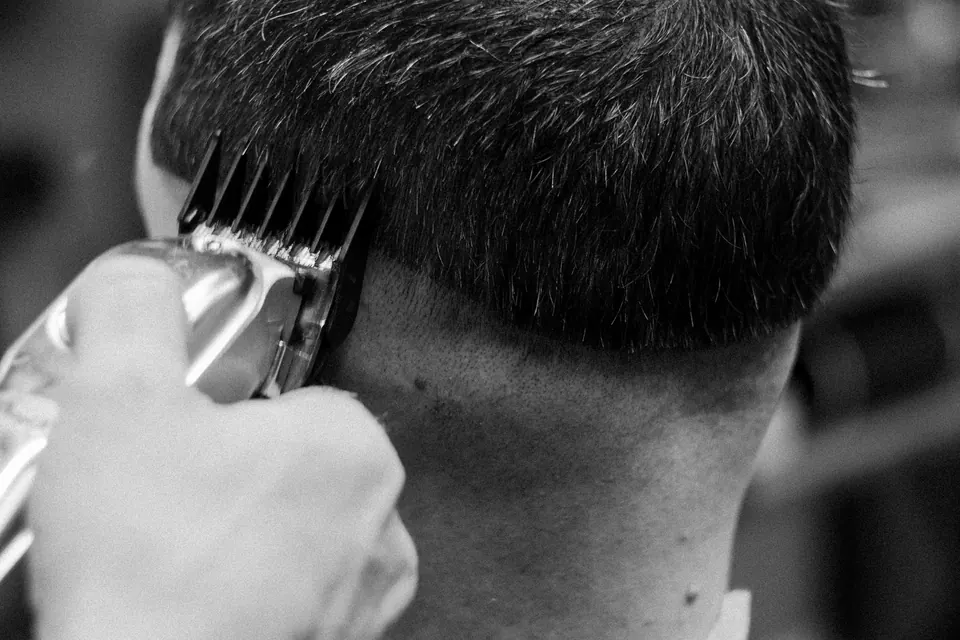 Schwarzweiß-Nahaufnahme: Clipper mit Aufsatzkamm zieht den Übergang im Nacken