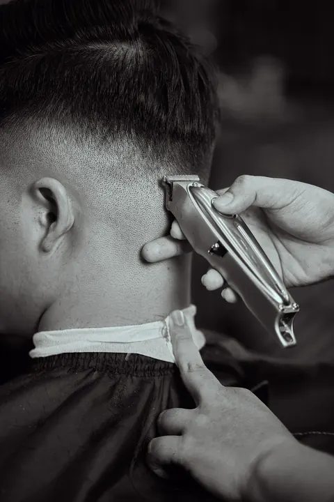 Schwarzweißaufnahme: Trimmer am Nacken bei einem Taper-Fade