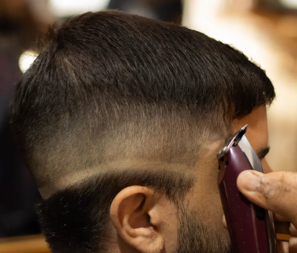 Seitenansicht eines Fade-Haarschnitts, der Clipper führt den Übergang